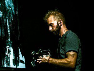 Man holding a camera in a low-lit setting.
