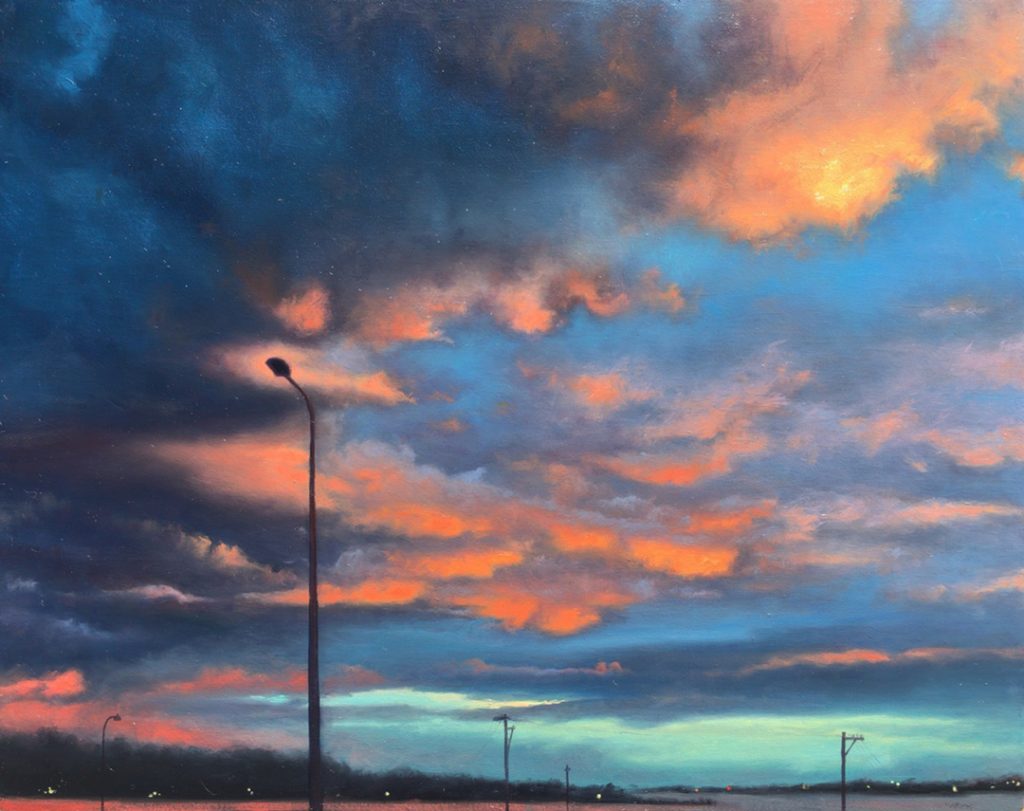 Colorful sunset with dramatic clouds and silhouetted streetlights.