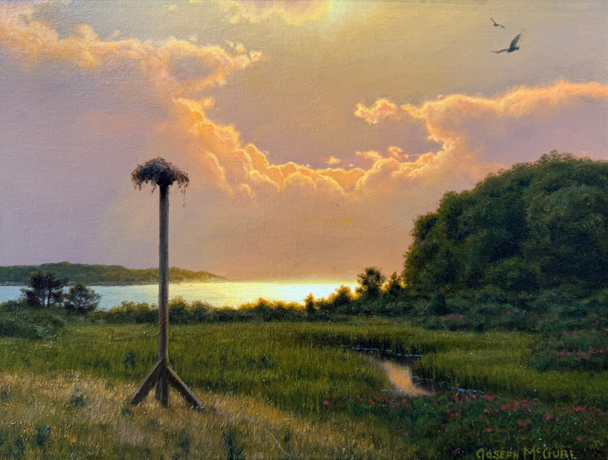 A serene lakeside sunset with a bird's nest on a tall wooden post.