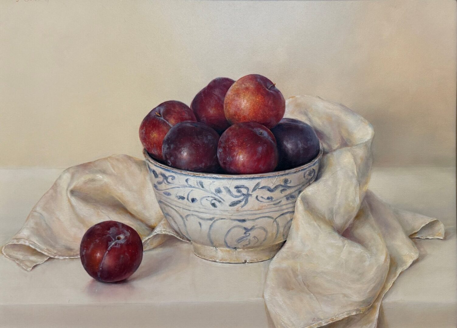 A bowl of ripe plums with a cloth beside it.