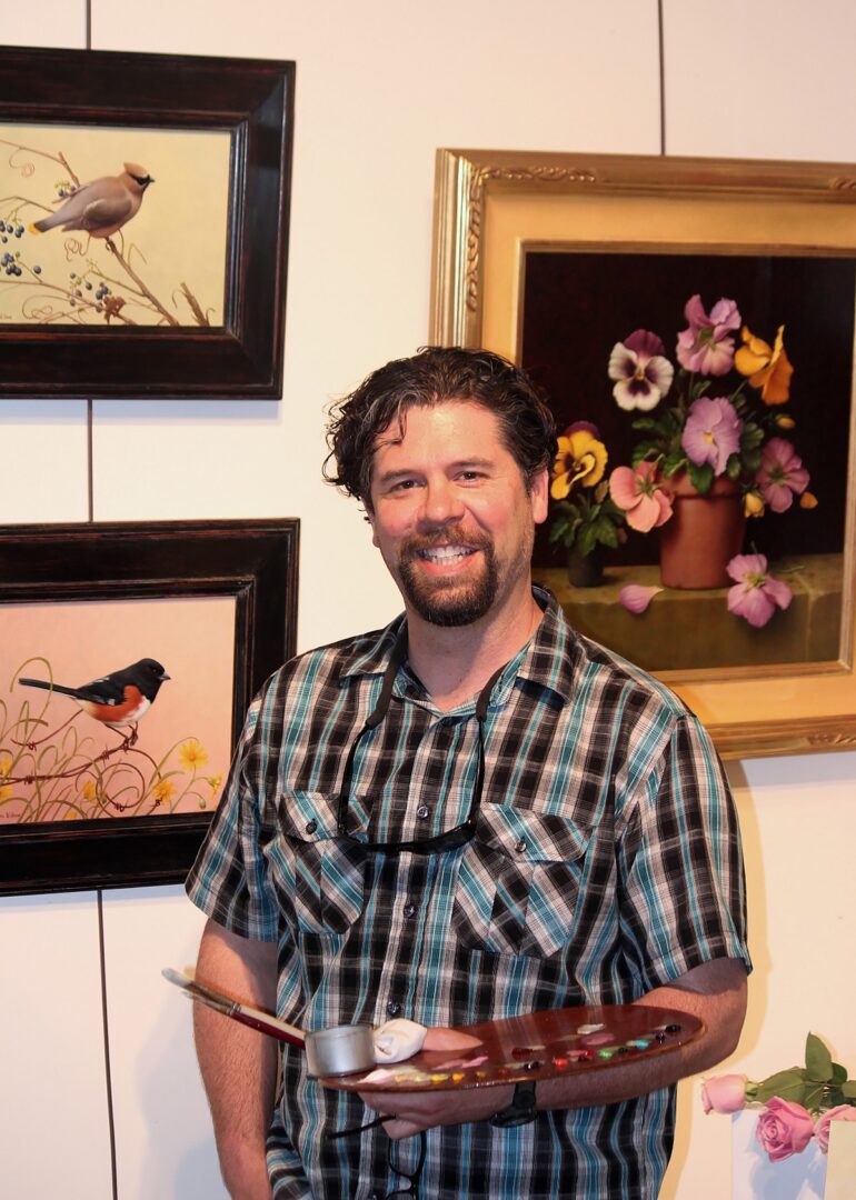 Artist holding palette in front of paintings