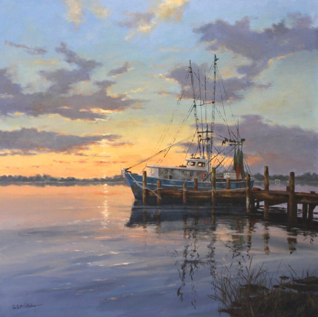 A fishing boat docked at sunset with calm waters reflecting the sky.