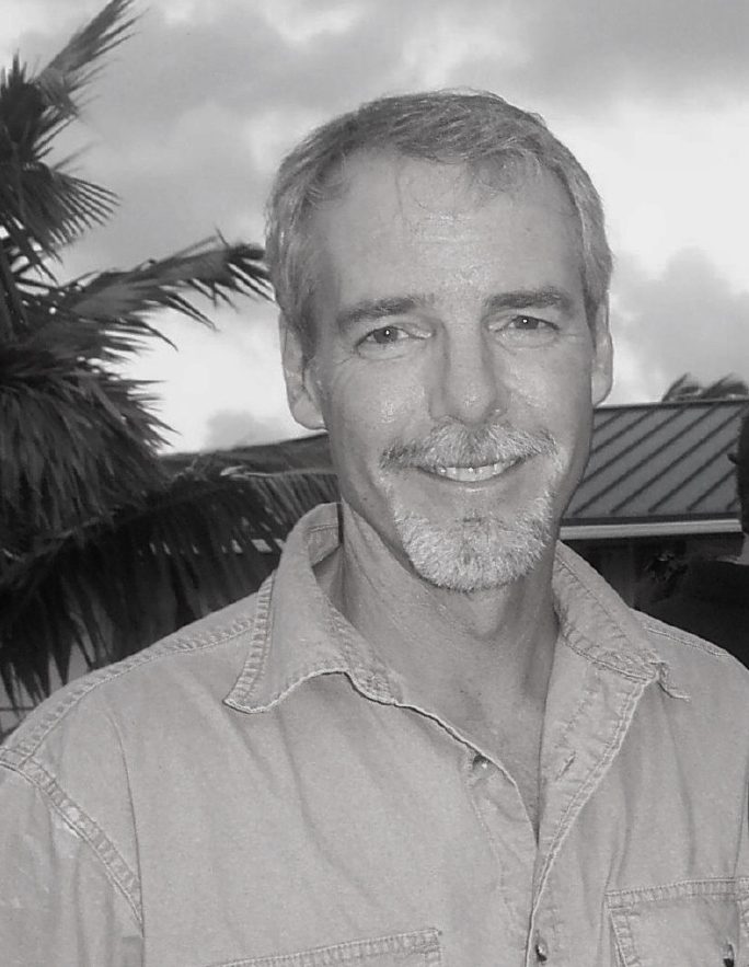 Smiling middle-aged man outdoors with palm trees in background.