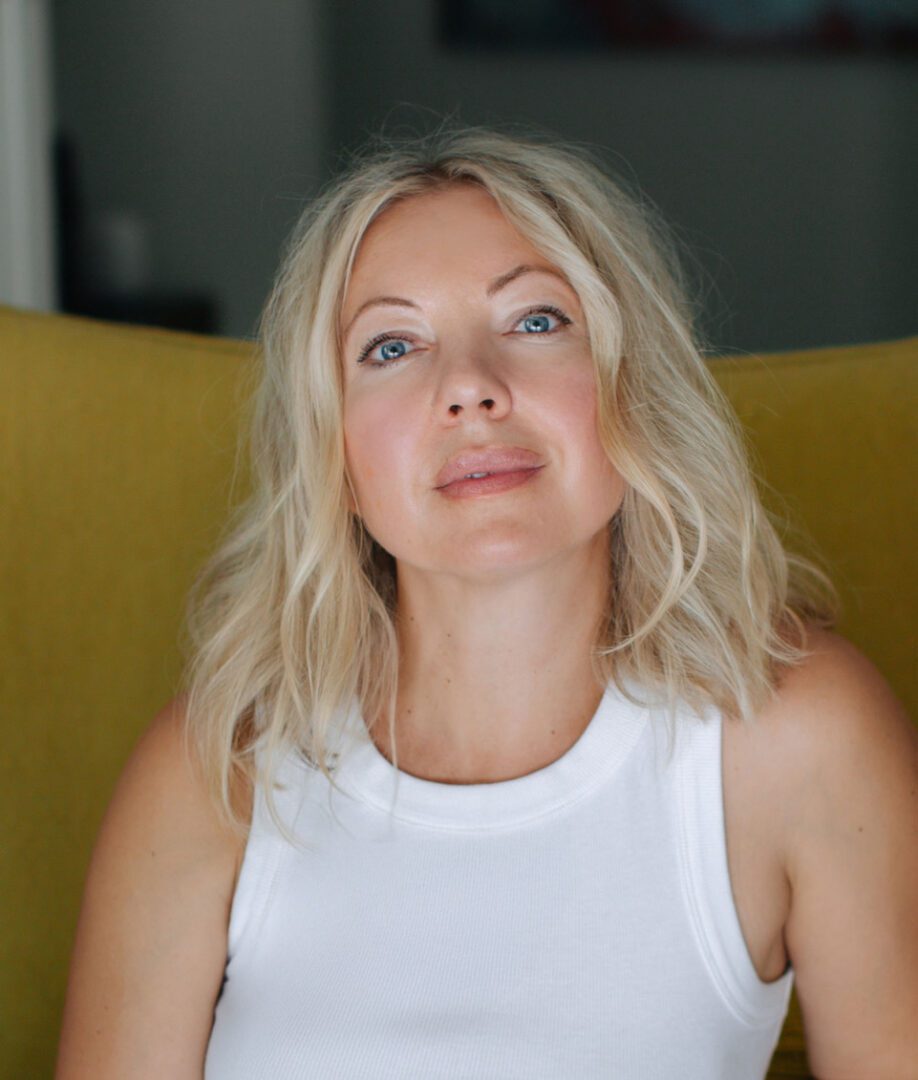 Portrait of a confident woman with blonde hair in a white top.