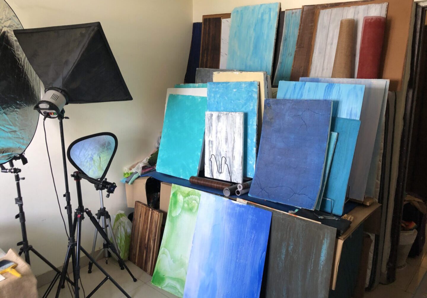 Studio with stacked abstract paintings and photography lighting equipment.