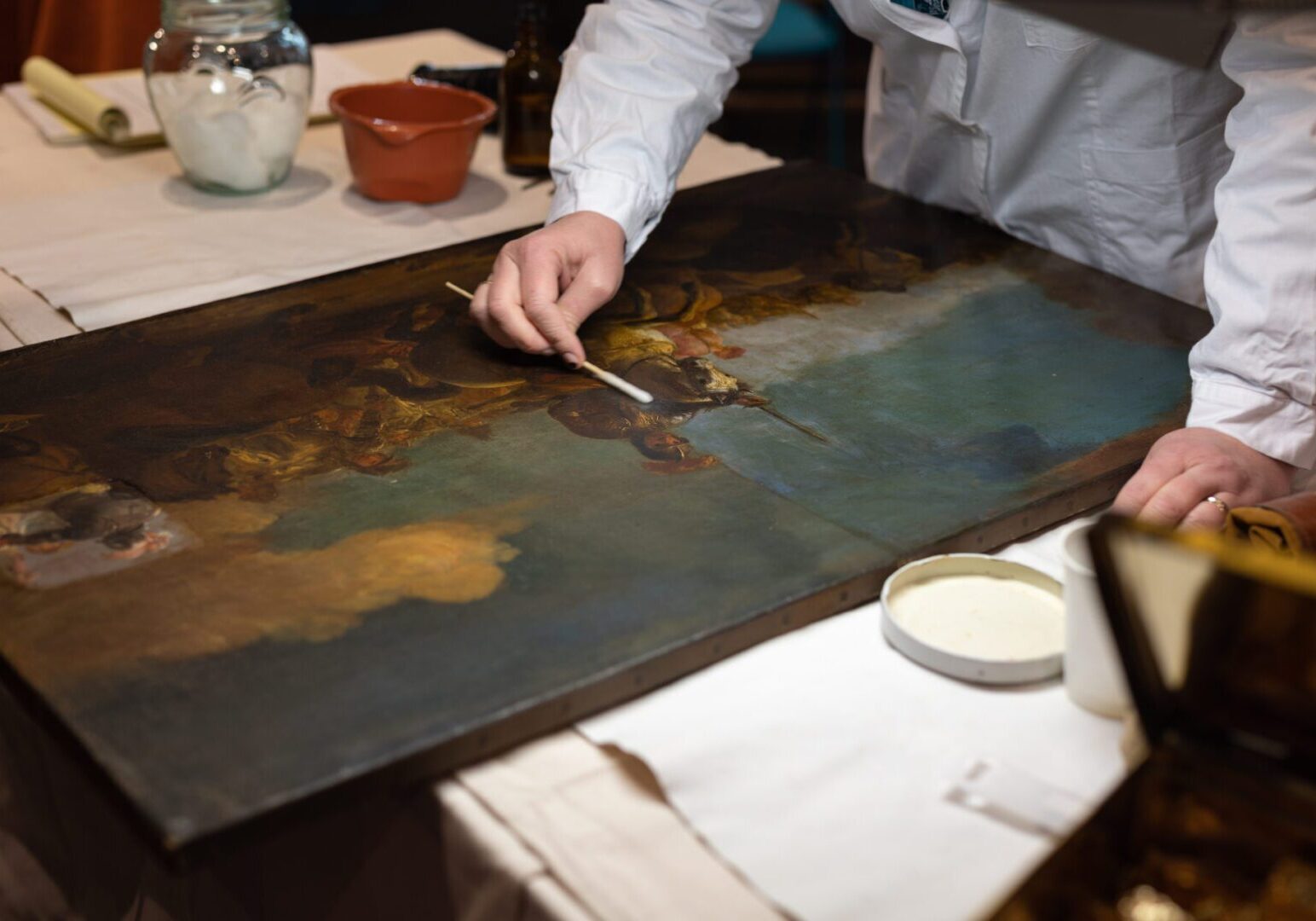 A person restoring an old painting with a brush.